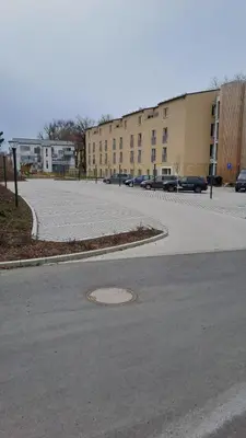 an empty parking lot with a building in the background at Apartmán u letiště in Tuchoměřice