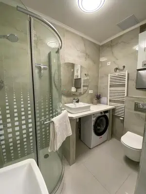 a bathroom with a shower sink and a washing machine at Apartment Ípák in Prague