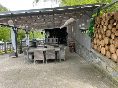 a patio with a table and chairs and a stack of logs at Marina Hubenov in Hubenov