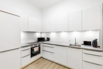 a white kitchen with white cabinets and appliances at Rentero Wenceslas Square Apartments in Prague