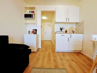 a kitchen and a living room with white cabinets at LIVE-INN PRAGUE DELUXE SUITE FOR 1-4 GUESTS, 20 Mins to center, Lift, Gym, Reception, Parking, Roof Terrace, Game & Party in Prague
