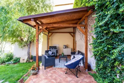 a wooden pavilion with chairs and a grill in a yard at Apartman u Rudolfa II in Brandýs nad Labem-Stará Boleslav