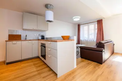 a kitchen with white cabinets and a chair in a room at Apartman u Rudolfa II in Brandýs nad Labem-Stará Boleslav