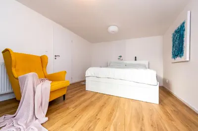 a bedroom with a bed and a yellow chair at Apartman u Rudolfa II in Brandýs nad Labem-Stará Boleslav