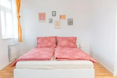 a bed with pink sheets in a white room at Cozy Retreat by Wenceslas Square in Prague