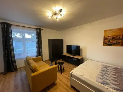 a bedroom with a bed and a couch and a tv at New Apartment near to Elbe bicycle path in Roudnice nad Labem