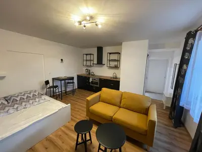 a living room with a yellow couch and a kitchen at New Apartment near to Elbe bicycle path in Roudnice nad Labem