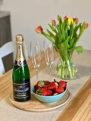 a bottle of champagne and a bowl of strawberries on a table at Apartmány Křivoklát in Křivoklát