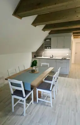 a kitchen with a wooden table and white chairs at Apartmány Křivoklát in Křivoklát