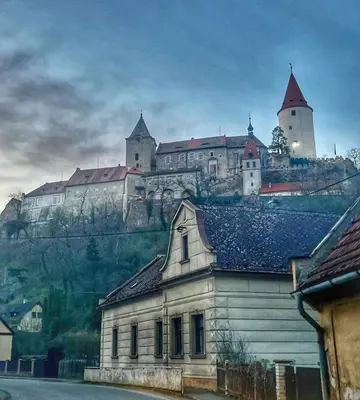a castle on top of a hill with a building at Apartmány Křivoklát in Křivoklát