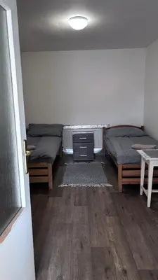 a room with two beds and a table and a door at Sleep & Go Czech Republic - Praha - západ in Jeneček