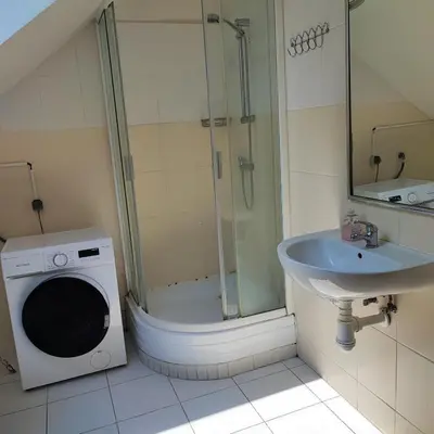 a bathroom with a shower and a washing machine and a sink at Sleep & Go Czech Republic - Praha - západ in Jeneček