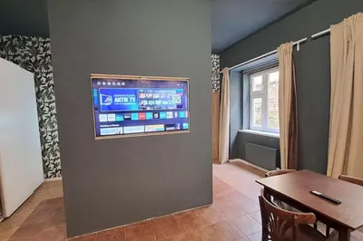 a living room with a table and a television on a wall at Contemporary Zizkov Studio -001- in Prague