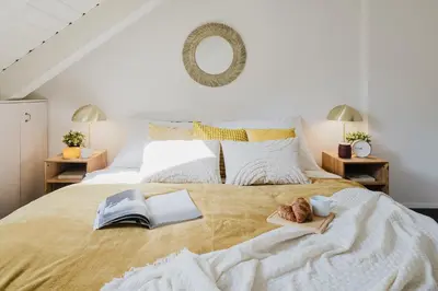 a bedroom with a bed with two books and a mirror at Prague Days - Attic Maisonette with Netflix and Workspace in New Town in Prague