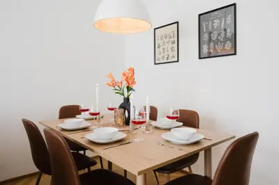 a dining room table with chairs and a wooden table with wine glasses at Prague Days - Two-bedroom Apartment with Parking Space and 2 bathrooms in Vinohrady in Prague