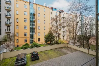 two cars parked in a parking lot in front of buildings at Prague Days - Two-bedroom Apartment with Parking Space and 2 bathrooms in Vinohrady in Prague