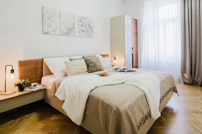 a white bedroom with a large bed with white sheets at Prague Days - Two-bedroom Apartment with Parking Space and 2 bathrooms in Vinohrady in Prague