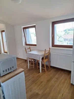 a living room with a table and chairs and two windows at Sleep & Go Czech Republic - Mořina in Mořina