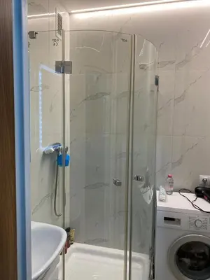 a bathroom with a shower and a sink and a washing machine at Near city center flat in Prague