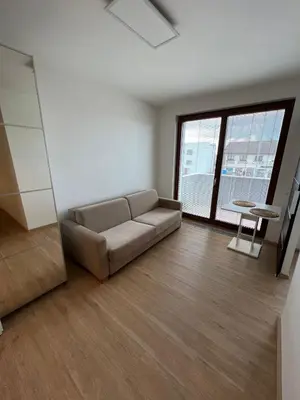 a living room with a couch and a large window at Bright & Cosy 1-Bedroom Apartment with Balcony in Prague
