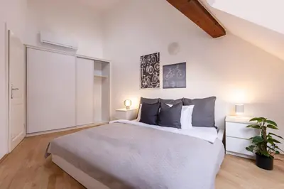 a white bedroom with a large bed and a plant at TurnKey I Old Town 5BR Loft Apartment in Prague