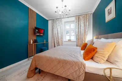 a bedroom with blue walls and a bed with orange pillows at WagnerStays 2BD Suites City Center Residence in Prague