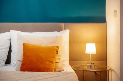 a bed with a yellow pillow and a side table at WagnerStays 2BD Suites City Center Residence in Prague