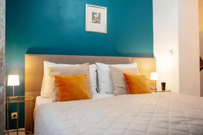 a bedroom with a large white bed with orange pillows at WagnerStays 2BD Suites City Center Residence in Prague
