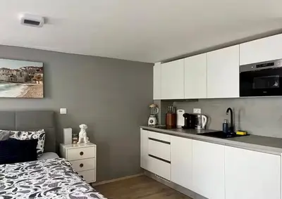 a kitchen with white cabinets and a bed in a room at Romantic apartment by the city center in Prague
