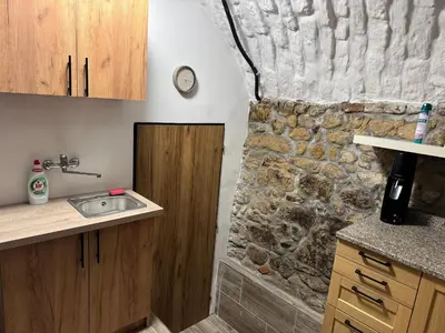 a kitchen with a sink and a stone wall at Suterénní apartmán na Hejtmánce u letiště v Mladé Boleslavi in Mladá Boleslav