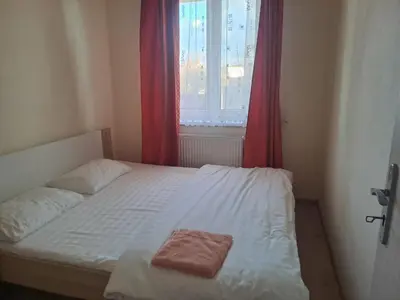 a bedroom with a white bed with a red curtain at HaKhanhFamily in Prague