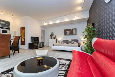 a living room with a bed and a red couch at Apartmán u parku Parukářka in Prague