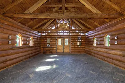 a large room with wooden walls and a ceiling with a chandelier at Ranči v Buši - pokoj ve srubu in Čím