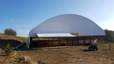 a large dome structure with a building in a field at Ranči v Buši - pokoj ve srubu in Čím