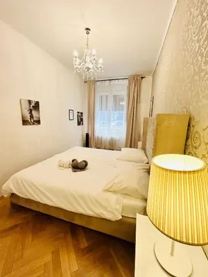 a bedroom with a bed with a chandelier and two tables at Luxury and cozy apartment Vinohrady Prague in Prague