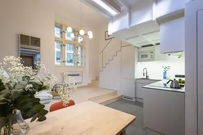 a kitchen with white cabinets and a wooden table at Rentero Designer Petite Stay, Prague in Prague