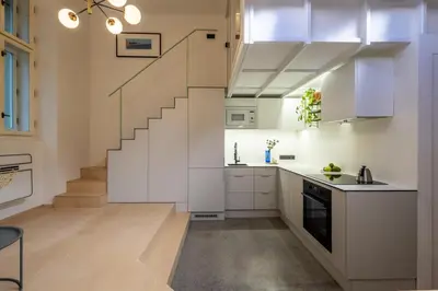 a kitchen with white cabinets and a staircase at Rentero Designer Petite Stay, Prague in Prague