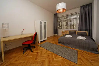 a bedroom with a bed and a desk and a chair at Apartments Vorsilska in Prague