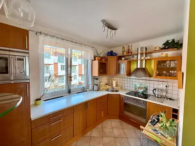 a kitchen with wooden cabinets and a large window at Útulný byt pár kroků od lázeňské fontány in Poděbrady
