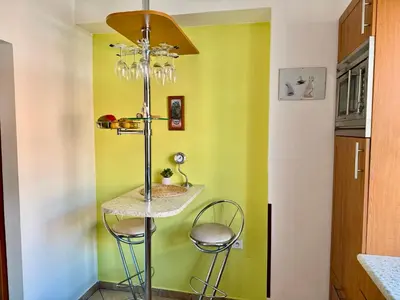 a small kitchen with a green wall and two stools at Útulný byt pár kroků od lázeňské fontány in Poděbrady
