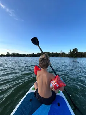 a young child sitting on a paddle board on the water at Útulný byt pár kroků od lázeňské fontány in Poděbrady