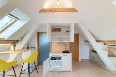 an attic kitchen with white cabinets and yellow chairs at TinyGreens B & B in Poděbrady