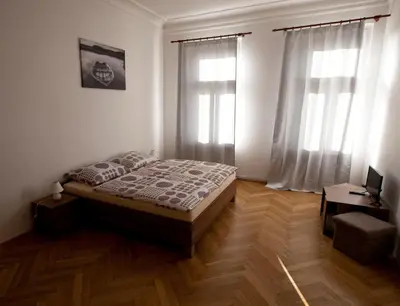 a bedroom with a bed and two windows at Carpe Diem Prague in Prague