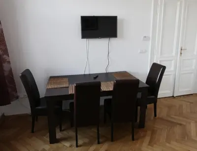 a dining room table with black chairs and a television on a wall at Carpe Diem Prague in Prague