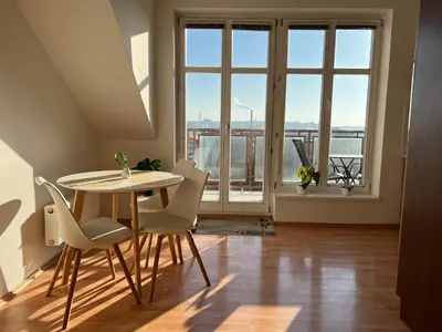 a dining room with a table and chairs and a large window at Rooftop Prague view apartment in Prague