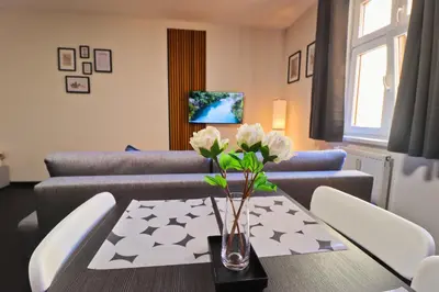 a living room with a table with a vase of flowers at A comfy apartment in Smíchov - Anděl in Prague