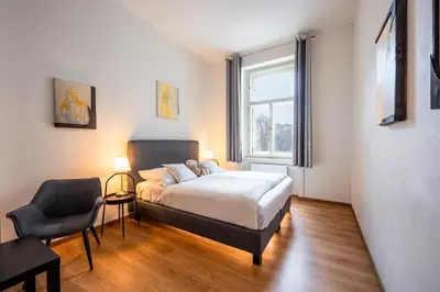 a bedroom with a bed and a chair and a window at PavlaCzech Art Apartment in Prague