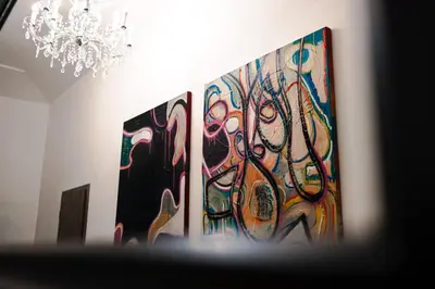 two paintings on the wall in a room with a chandelier at PavlaCzech Art Apartment in Prague