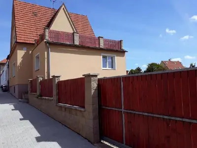 a house with a red fence next to a building at Apartment Patera in Unhošť