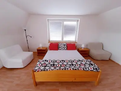 a bedroom with a bed and a couch and a window at Apartment Patera in Unhošť